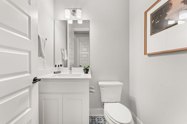 bathroom with baseboards, vanity, and toilet