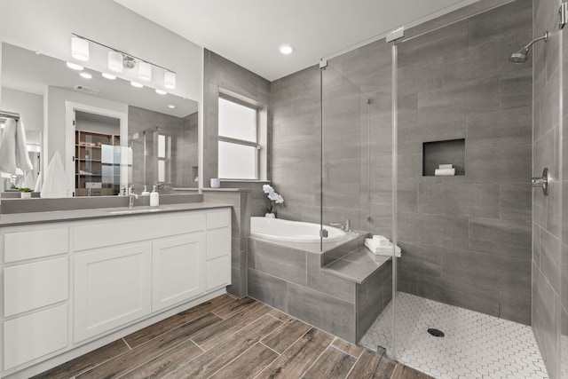 full bath featuring a garden tub, visible vents, a stall shower, wood tiled floor, and vanity