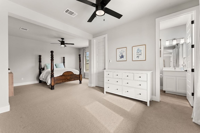 bedroom featuring light colored carpet, visible vents, ensuite bath, and baseboards