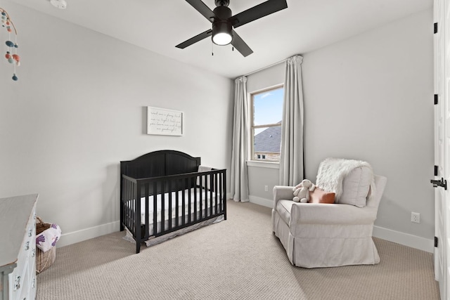 carpeted bedroom featuring ceiling fan, a crib, and baseboards