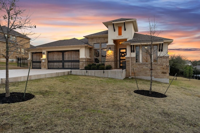 prairie-style house with a garage, driveway, stone siding, fence, and a front yard