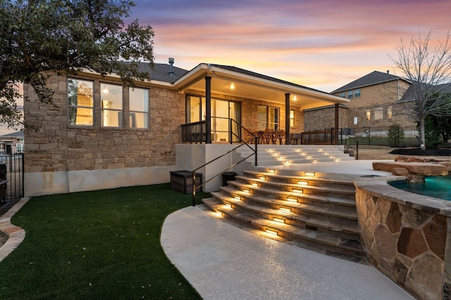 view of front facade with stone siding, fence, and a lawn