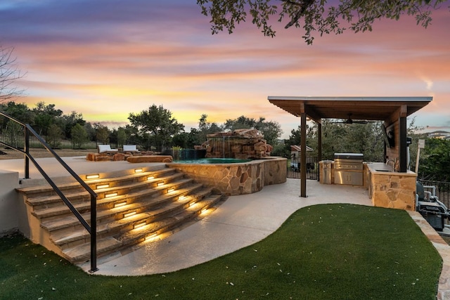 view of patio with exterior kitchen, area for grilling, and a sink