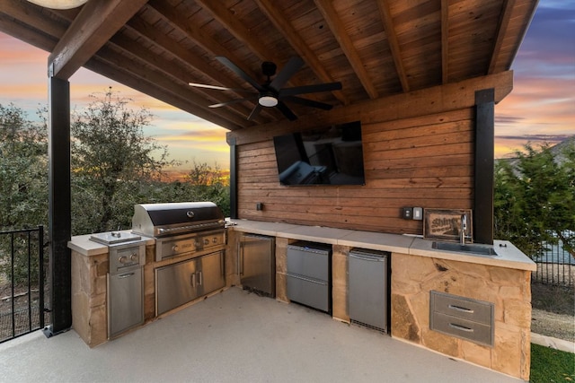 view of patio with ceiling fan, exterior kitchen, a sink, and a grill