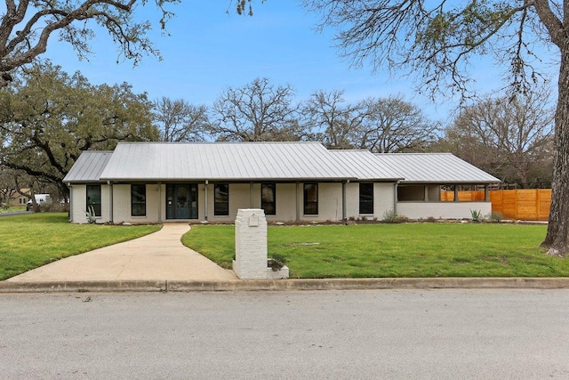 view of front facade with metal roof, fence, a front lawn, and brick siding