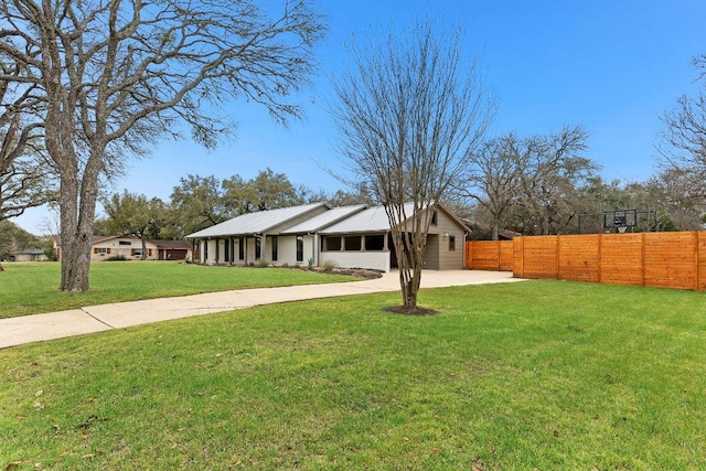 view of front of house featuring driveway, fence, and a front lawn