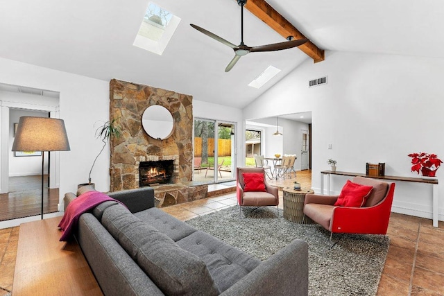 living room with a skylight, visible vents, beamed ceiling, a fireplace, and high vaulted ceiling