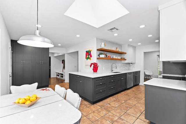 kitchen with a sink, visible vents, light countertops, stainless steel dishwasher, and tasteful backsplash