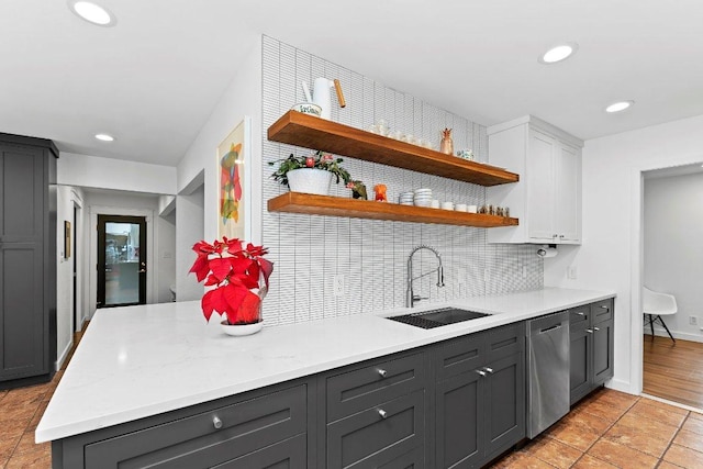 kitchen with light countertops, decorative backsplash, white cabinets, a sink, and dishwasher