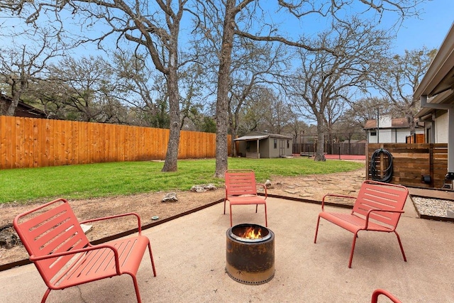 view of patio featuring an outbuilding, a fire pit, and a fenced backyard