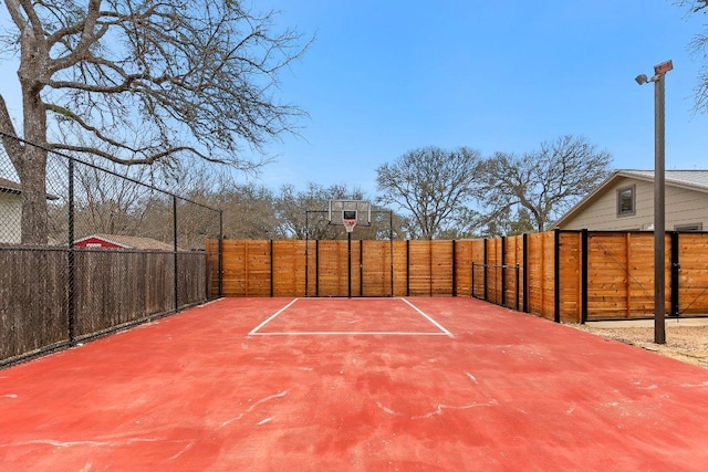 view of basketball court with basketball hoop and fence