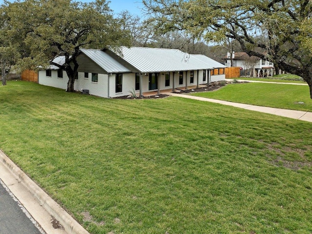 ranch-style house featuring a front yard, a standing seam roof, and metal roof