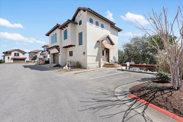 exterior space with a tiled roof, uncovered parking, and stucco siding