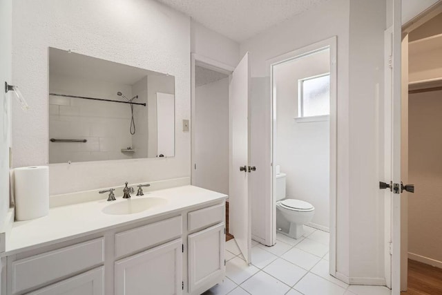 bathroom featuring tile patterned floors, a textured ceiling, toilet, and vanity