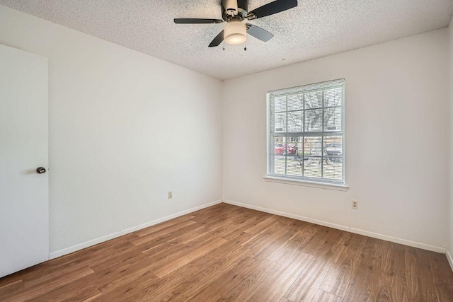 unfurnished room with a textured ceiling, wood finished floors, and baseboards