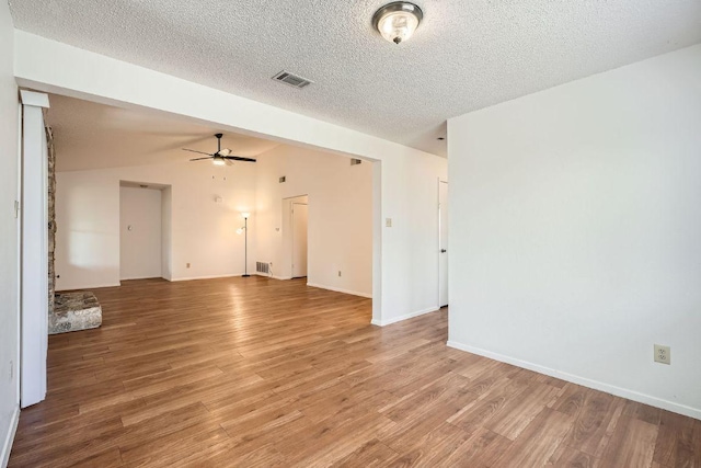 unfurnished living room featuring light wood-type flooring, visible vents, a ceiling fan, and lofted ceiling