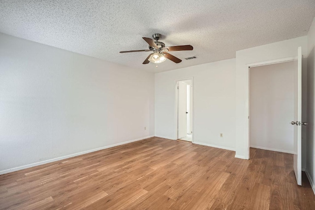 unfurnished room featuring a textured ceiling, a ceiling fan, visible vents, baseboards, and light wood-type flooring