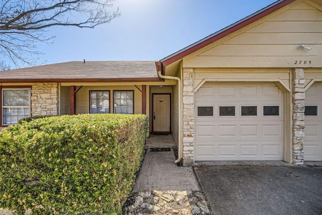 ranch-style house with a garage, stone siding, and roof with shingles