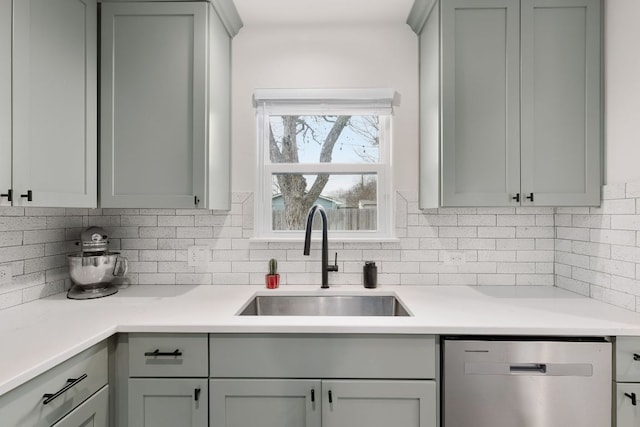 kitchen with dishwasher, light countertops, a sink, and decorative backsplash