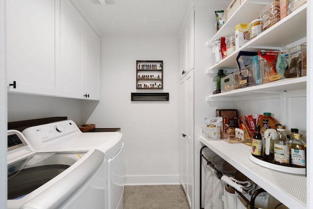 clothes washing area with washing machine and dryer, cabinet space, and baseboards