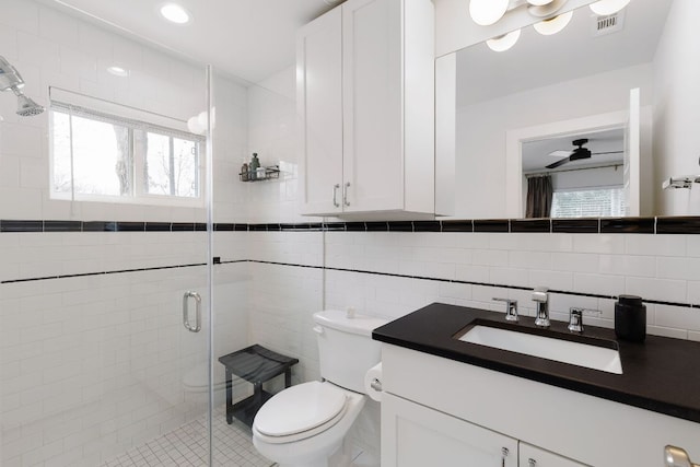 bathroom with toilet, a shower stall, tile walls, and a wealth of natural light