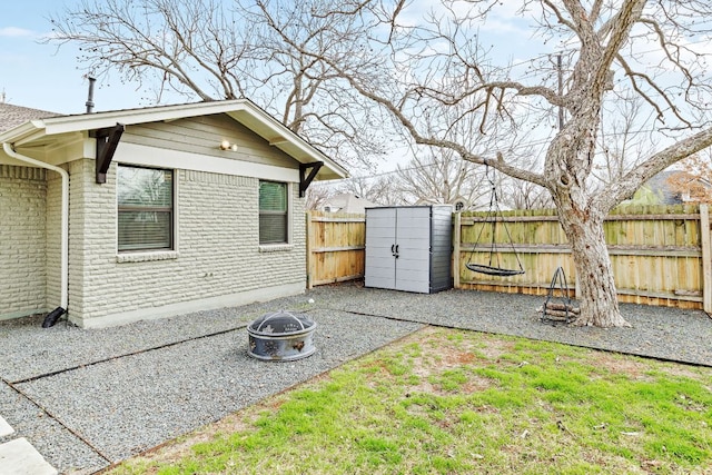 view of yard featuring a patio, a storage unit, an outdoor fire pit, a fenced backyard, and an outdoor structure