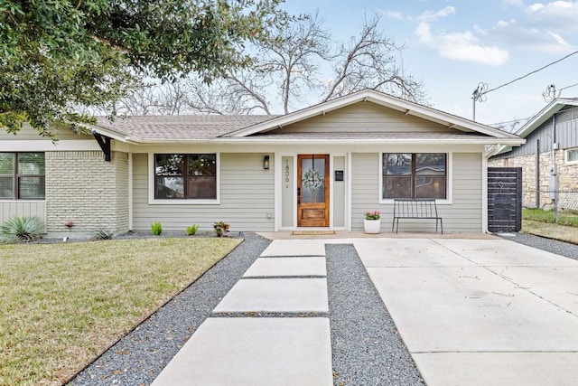 ranch-style home with brick siding, roof with shingles, and a front yard