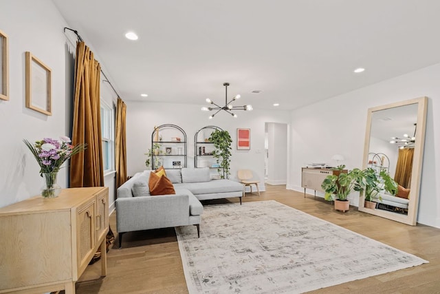 living area with recessed lighting, light wood-type flooring, and an inviting chandelier