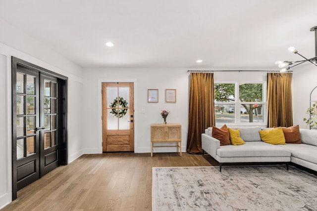 living area featuring light wood-style flooring, baseboards, a chandelier, and recessed lighting