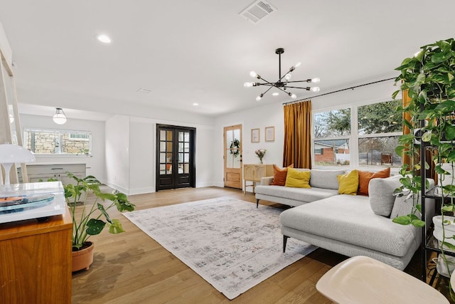 living room featuring a wealth of natural light, french doors, visible vents, and light wood-style floors