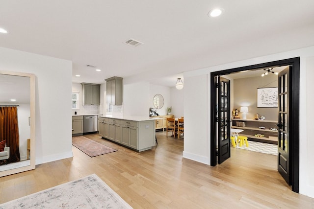 kitchen featuring light countertops, visible vents, light wood-style flooring, stainless steel dishwasher, and gray cabinetry