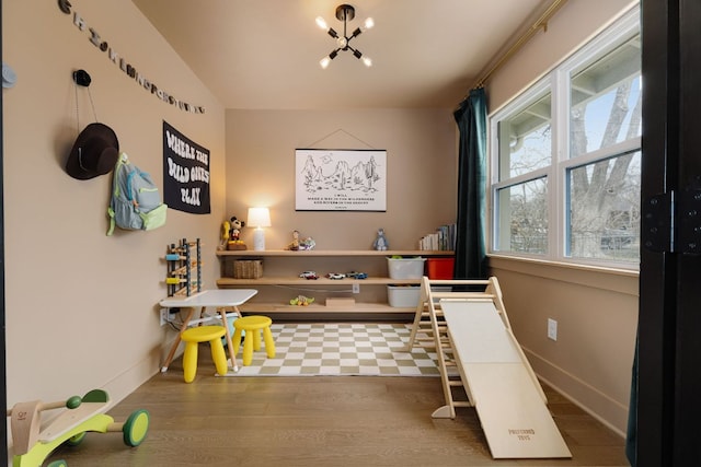 interior space featuring lofted ceiling, baseboards, a chandelier, and wood finished floors