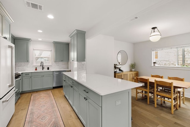 kitchen featuring stainless steel appliances, visible vents, a sink, and light wood finished floors