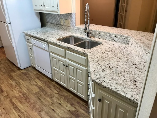 kitchen featuring light stone counters, dark wood-style flooring, decorative backsplash, a sink, and white appliances