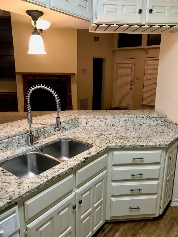 kitchen featuring dark wood finished floors, light stone counters, white cabinets, and a sink