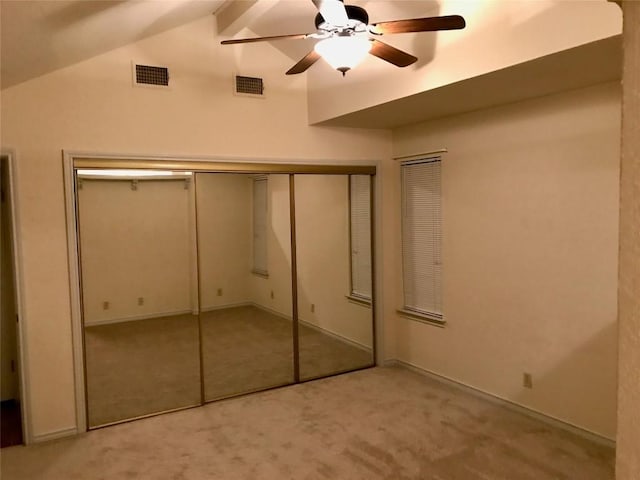 unfurnished bedroom with vaulted ceiling with beams, light carpet, visible vents, and a closet