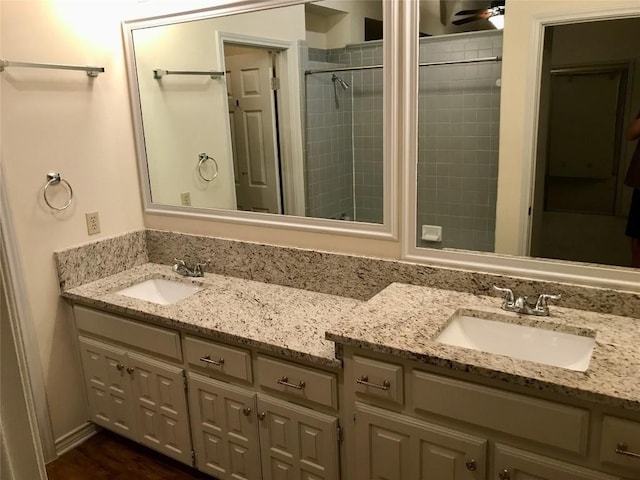 bathroom with a sink, a tile shower, and double vanity