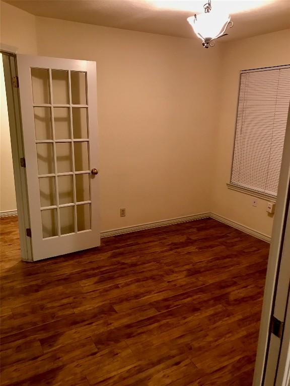 spare room with baseboards and wood finished floors