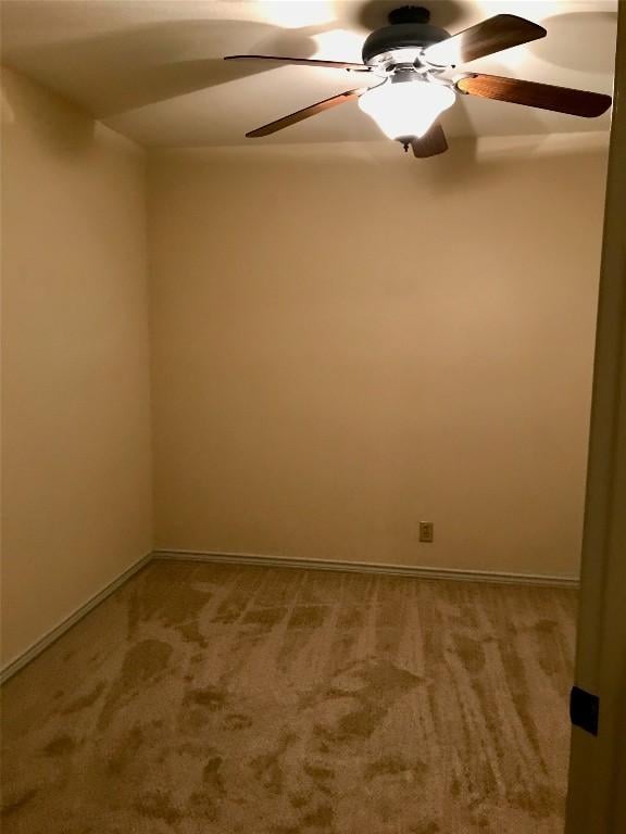 carpeted spare room with baseboards and a ceiling fan