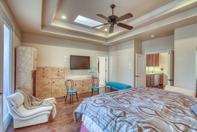 bedroom featuring ornamental molding, a tray ceiling, a skylight, and wood finished floors