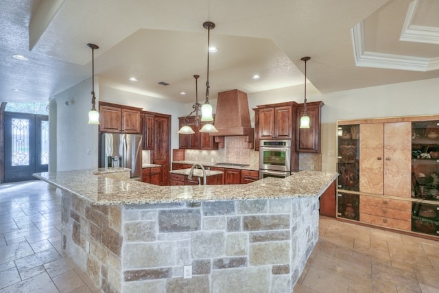 kitchen featuring stone tile floors, stainless steel appliances, a spacious island, french doors, and custom range hood