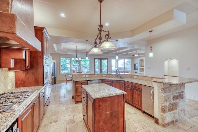 kitchen with a large island with sink, stainless steel appliances, a sink, backsplash, and stone tile flooring