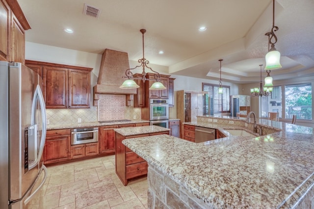 kitchen featuring custom exhaust hood, stainless steel appliances, a spacious island, a raised ceiling, and a sink