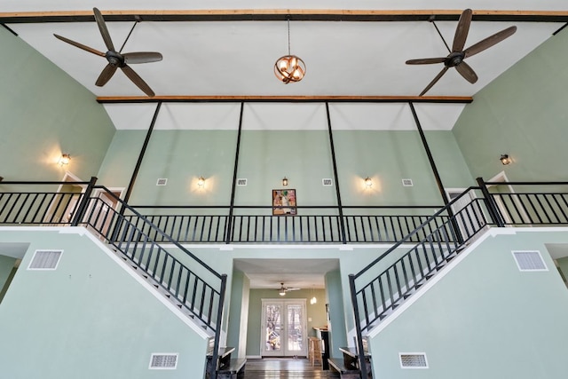 stairs featuring visible vents, ceiling fan, french doors, and a high ceiling