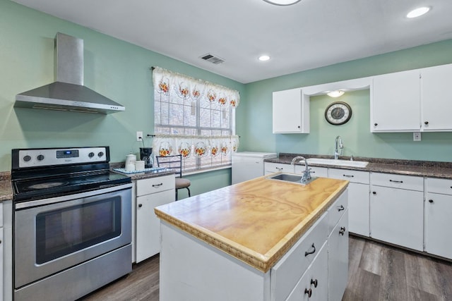 kitchen featuring visible vents, stainless steel range with electric cooktop, a sink, and wall chimney range hood