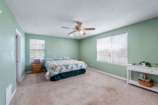 carpeted bedroom featuring baseboards, visible vents, and a ceiling fan