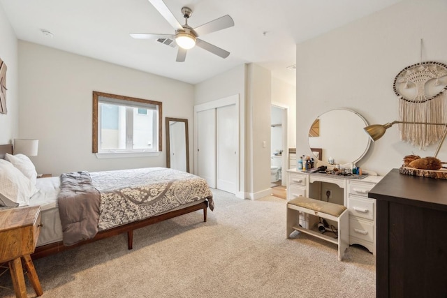 bedroom with baseboards, light colored carpet, ensuite bath, ceiling fan, and a closet