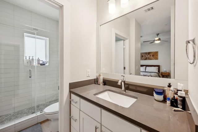 bathroom with a stall shower, visible vents, toilet, ceiling fan, and vanity