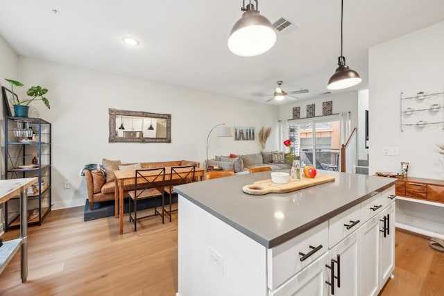 kitchen with a ceiling fan, visible vents, white cabinetry, light wood finished floors, and pendant lighting