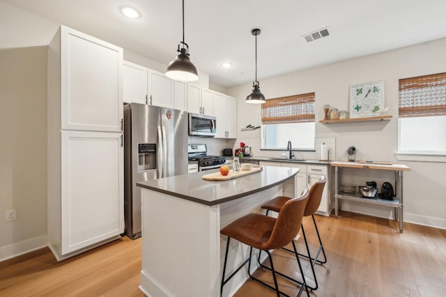 kitchen with visible vents, light wood-style flooring, a breakfast bar area, stainless steel appliances, and a sink